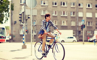 Image showing young hipster man with bag riding fixed gear bike