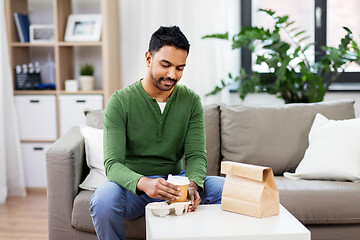 Image showing indian man with takeaway coffee and food at home