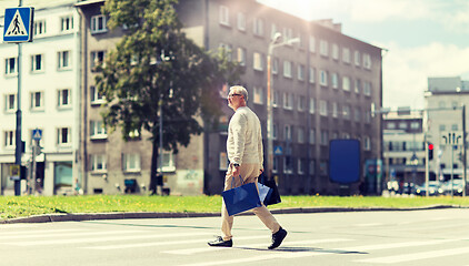 Image showing senior man with shopping bags walking on crosswalk