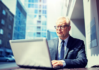 Image showing senior businessman with laptop at city street cafe