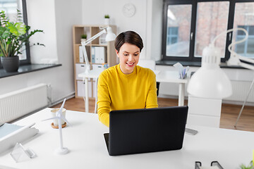 Image showing happy businesswoman with laptop working at office