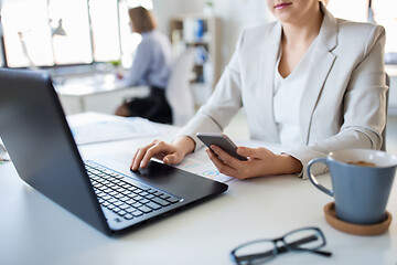 Image showing businesswoman with smartphone and laptop at office