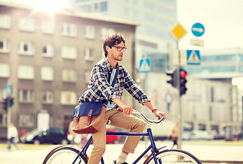 Image showing young hipster man with bag riding fixed gear bike