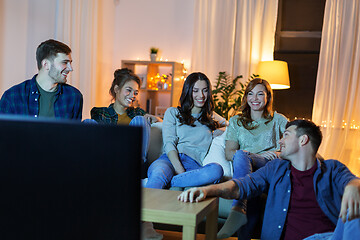 Image showing happy friends watching tv at home in evening