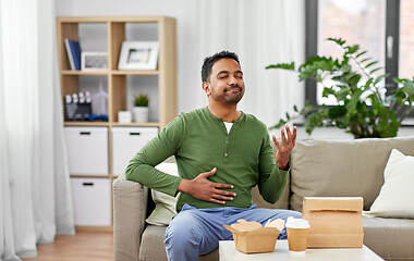 Image showing pleased indian man eating takeaway food at home