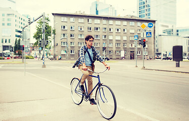 Image showing young hipster man with bag riding fixed gear bike