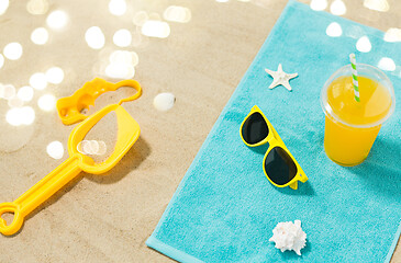 Image showing sunglasses, sand toys and juice on beach towel