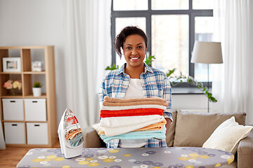 Image showing african american woman with ironed linen at home