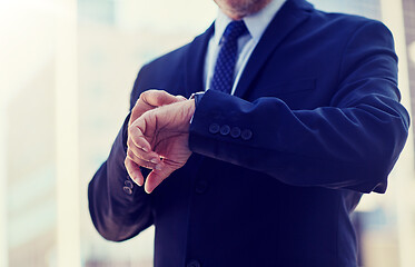 Image showing senior businessman with wristwatch on city street