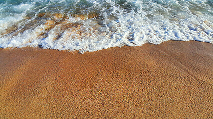 Image showing Sea wave with white foam on the sandy beach