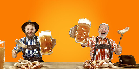 Image showing Smiling men with beer dressed in traditional Austrian or Bavarian costume holding mug of beer at pub or studio. The celebration, oktoberfest, festival