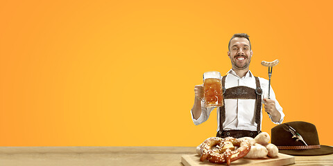 Image showing Smiling man with beer dressed in traditional Austrian or Bavarian costume holding mug of beer at pub or studio. The celebration, oktoberfest, festival