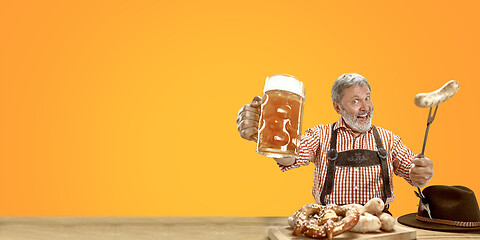 Image showing Smiling senior man with beer dressed in traditional Austrian or Bavarian costume holding mug of beer at pub or studio. The celebration, oktoberfest, festival