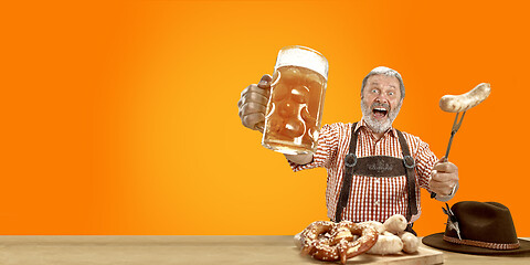 Image showing Smiling senior man with beer dressed in traditional Austrian or Bavarian costume holding mug of beer at pub or studio. The celebration, oktoberfest, festival