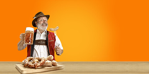 Image showing Smiling senior man with beer dressed in traditional Austrian or Bavarian costume holding mug of beer at pub or studio. The celebration, oktoberfest, festival