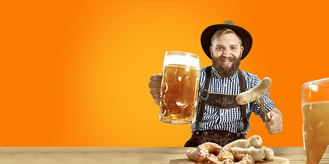 Image showing Smiling man with beer dressed in traditional Austrian or Bavarian costume holding mug of beer at pub or studio. The celebration, oktoberfest, festival