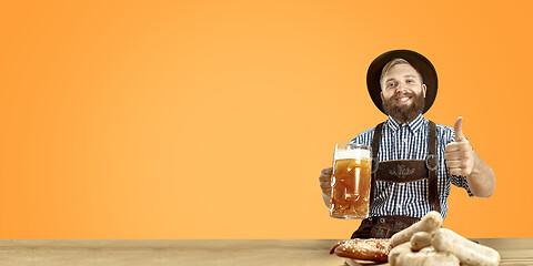 Image showing Smiling man with beer dressed in traditional Austrian or Bavarian costume holding mug of beer at pub or studio. The celebration, oktoberfest, festival