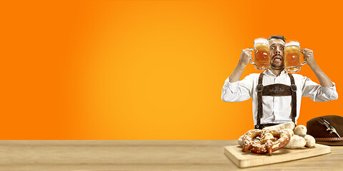 Image showing Smiling man with beer dressed in traditional Austrian or Bavarian costume holding mug of beer at pub or studio. The celebration, oktoberfest, festival