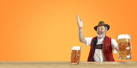 Image showing Smiling senior man with beer dressed in traditional Austrian or Bavarian costume holding mug of beer at pub or studio. The celebration, oktoberfest, festival