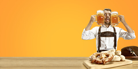 Image showing Smiling man with beer dressed in traditional Austrian or Bavarian costume holding mug of beer at pub or studio. The celebration, oktoberfest, festival