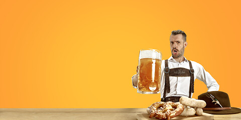 Image showing Smiling man with beer dressed in traditional Austrian or Bavarian costume holding mug of beer at pub or studio. The celebration, oktoberfest, festival