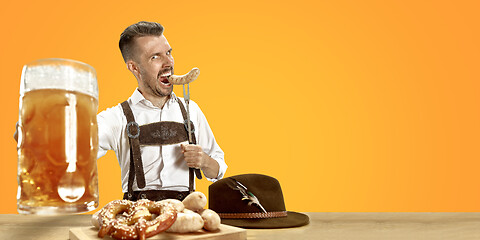 Image showing Smiling man with beer dressed in traditional Austrian or Bavarian costume holding mug of beer at pub or studio. The celebration, oktoberfest, festival