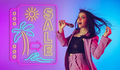 Image showing Caucasian female singer portrait isolated on gradient studio background in neon light with neon sign