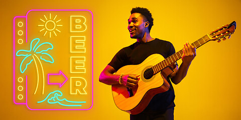 Image showing Young musician playing guitar in neon light on gradient background, inspired, artwork