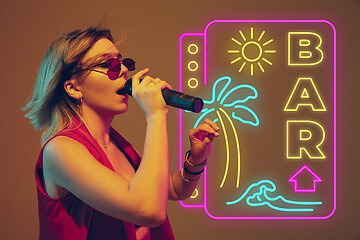 Image showing Caucasian female singer portrait isolated on gradient studio background in neon light with neon sign