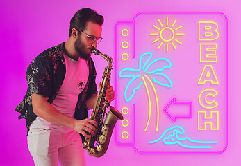 Image showing Young jazz musician playing the saxophone in neon light with neon sign