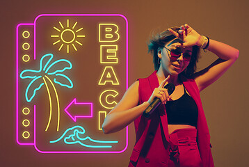 Image showing Caucasian female singer portrait isolated on gradient studio background in neon light with neon sign