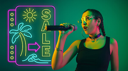 Image showing Caucasian female singer portrait isolated on gradient studio background in neon light with neon sign