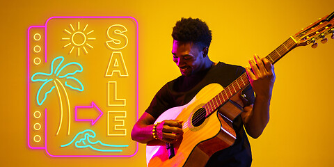 Image showing Young musician playing guitar in neon light on gradient background, inspired, artwork