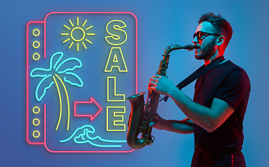 Image showing Young jazz musician playing the saxophone in neon light with neon sign