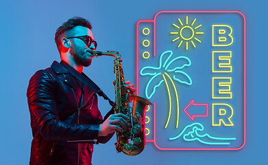 Image showing Young jazz musician playing the saxophone in neon light with neon sign