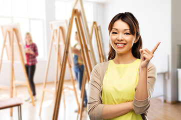 Image showing happy asian woman pointing finger up