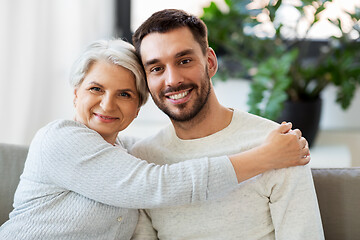 Image showing senior mother with adult son hugging at home