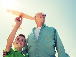 Image showing senior man and boy with toy airplane over sky