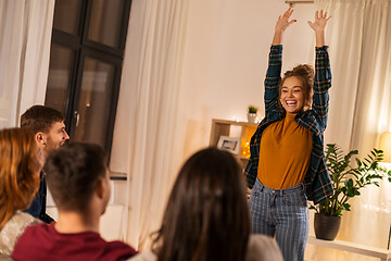 Image showing happy friends playing charades at home in evening