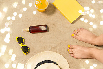 Image showing feet, hat, shades, sunscreen and juice on beach