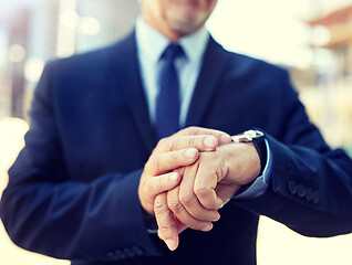 Image showing senior businessman with wristwatch on city street