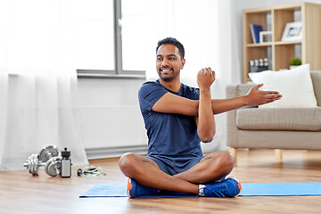 Image showing man training and stretching arm at home