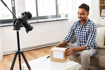 Image showing male video blogger opening parcel box at home