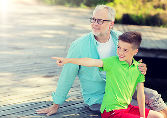 Image showing grandfather and grandson sitting on river berth