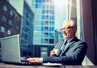 Image showing senior businessman with laptop drinking coffee