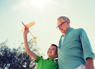 Image showing senior man and boy with toy airplane over sky