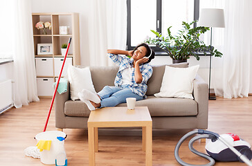 Image showing woman in headphones resting after home cleaning