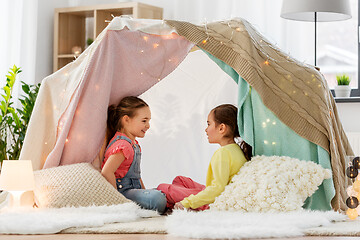 Image showing happy girls lying in kids tent and talking at home