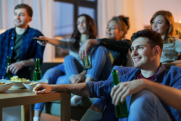 Image showing happy friends with drinks watching tv at home