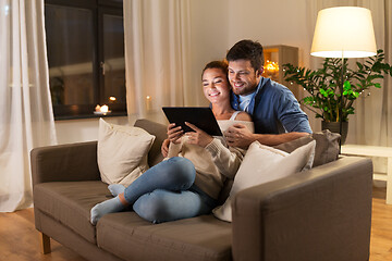 Image showing happy couple using tablet pc at home in evening